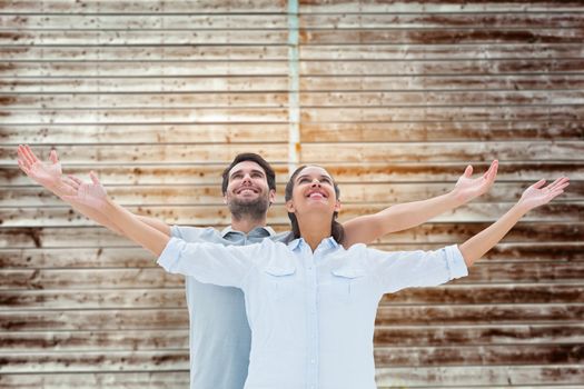 Cute couple standing with arms out against wooden planks