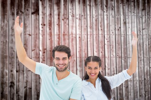 Cute couple sitting with arms raised against wooden planks