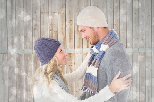Attractive couple in winter fashion hugging against grey abstract light spot design