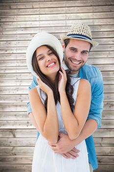 Happy hipster couple smiling at camera against wooden planks background