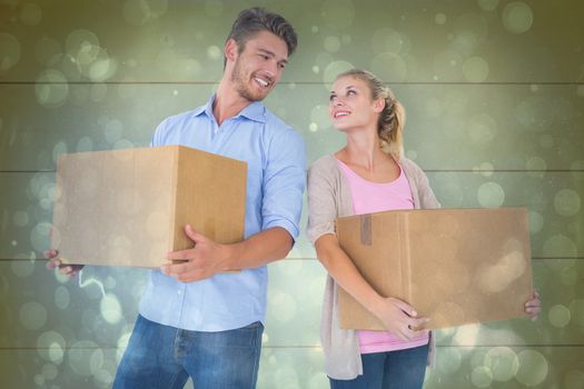 Attractive young couple carrying moving boxes against blue abstract light spot design