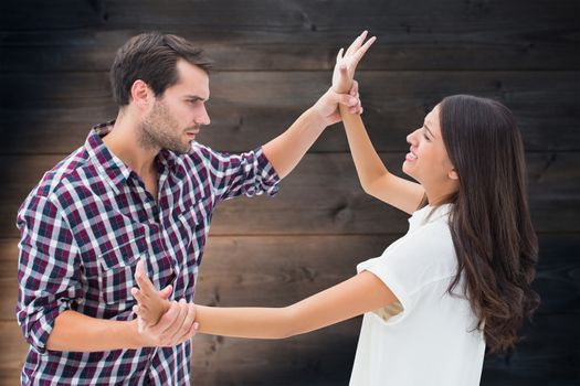 Fearful brunette being overpowered by boyfriend against wooden planks background