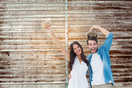 Happy hipster couple smiling at camera and cheering against wooden planks