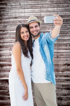 Happy hipster couple taking a selfie against wooden planks