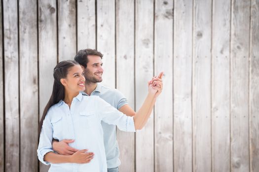Cute couple embracing and pointing against wooden planks
