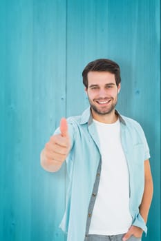 Happy casual man showing thumbs up against wooden planks background