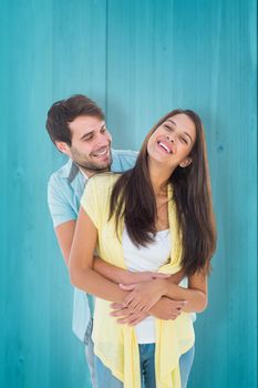 Happy casual couple smiling and hugging against wooden planks background