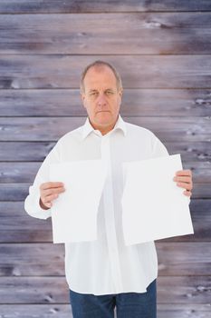 Serious man holding torn sheet of paper against faded grey wooden planks