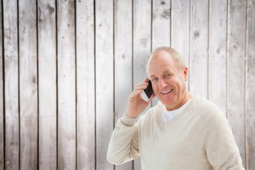 Happy mature man on the phone against wooden planks