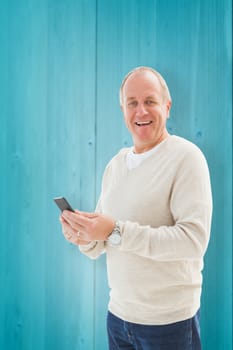 Happy mature man sending a text against wooden planks background