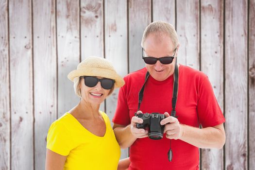 Happy mature couple wearing sunglasses against wooden planks