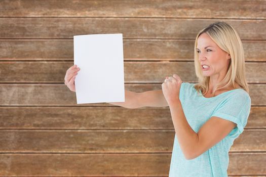 Angry woman holding piece of paper against wooden planks background