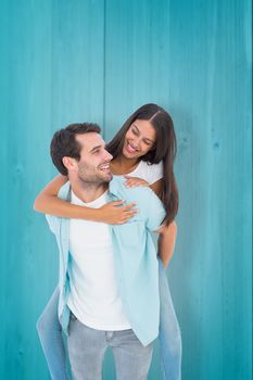 Happy casual man giving pretty girlfriend piggy back against wooden planks background