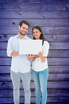 Attractive young couple holding their laptop against wooden planks background