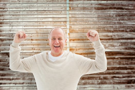 Happy mature man cheering at camera against wooden planks