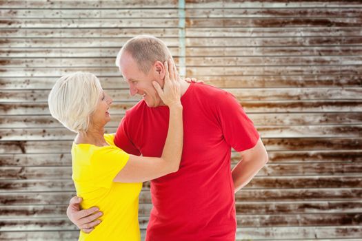 Happy mature couple hugging and smiling against wooden planks