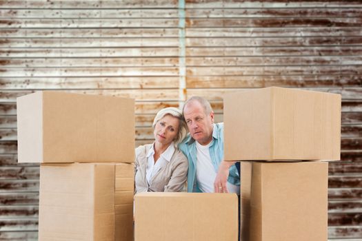Stressed older couple with moving boxes against wooden planks