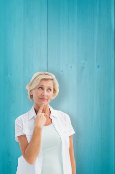 Mature woman thinking with hand on chin against wooden planks background