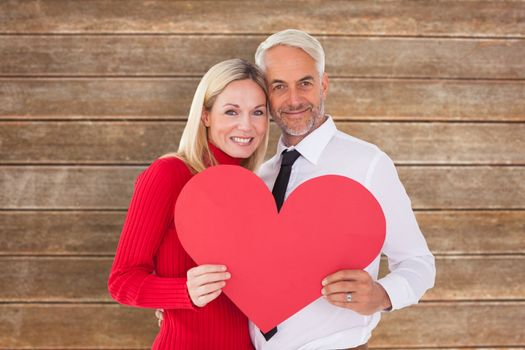 Handsome man getting a heart card form wife against wooden planks background