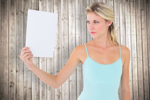 Angry blonde holding a sheet of paper against wooden planks background