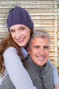 Happy couple in warm clothing against faded pine wooden planks