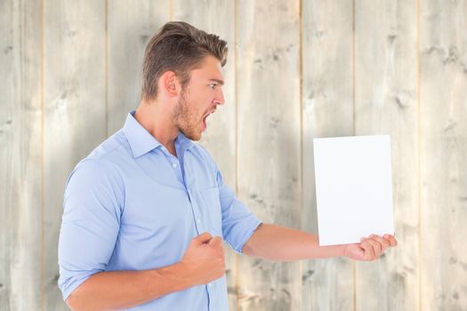 Angry man looking at page against pale wooden planks