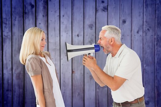 Angry man shouting at girlfriend through megaphone against wooden planks background