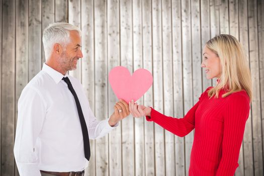 Handsome man getting a heart card form wife against wooden planks background