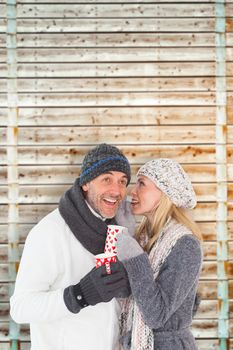 Happy couple in winter fashion holding mugs against wooden background in pale wood