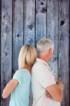 Unhappy couple not speaking to each other  against grey wooden planks