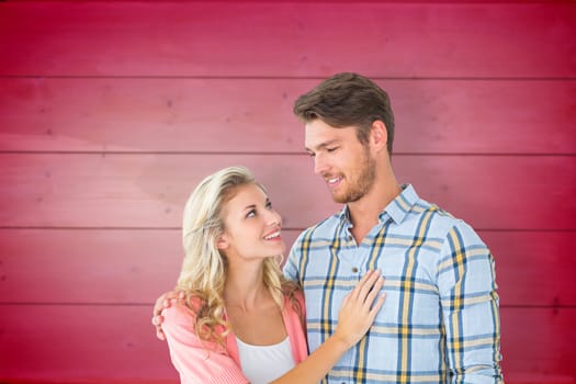 Attractive young couple smiling at each other against wooden planks background