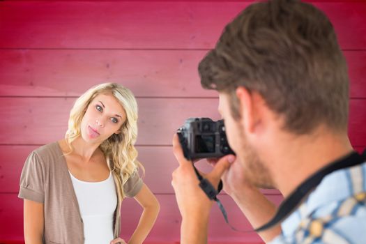 Man taking photo of his girlfriend sticking her tongue out against wooden planks background