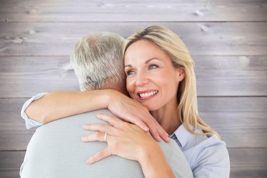 Happy couple standing and hugging against wooden planks background