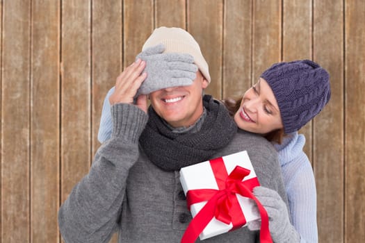 Woman surprising husband with gift against wooden planks