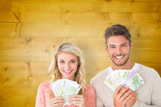 Attractive couple flashing their cash against wooden planks background