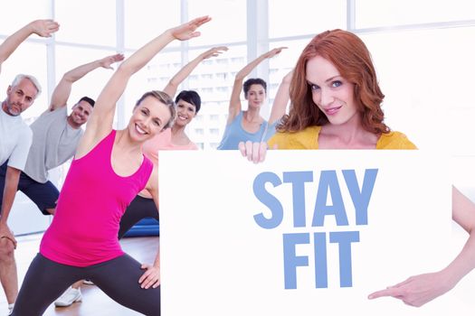 Pretty redhead showing a poster against stay fit