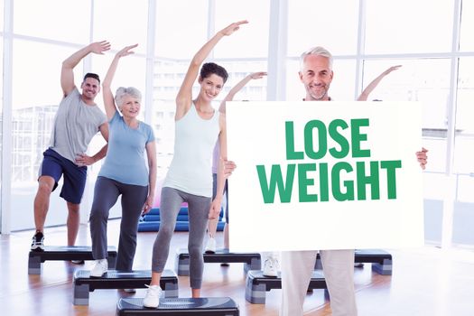 Smiling man showing large poster against lose weight