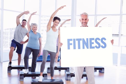 Smiling man showing large poster against fitness