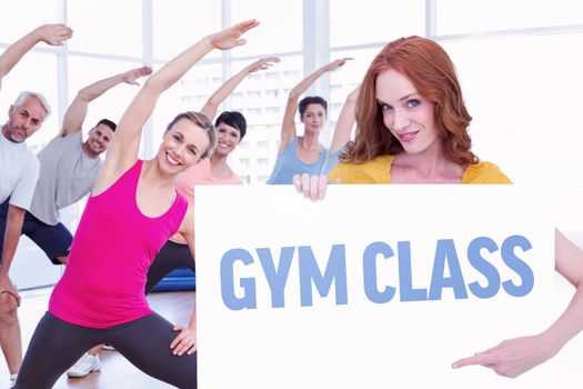 Pretty redhead showing a poster against gym class