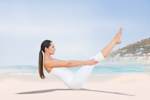 Toned woman doing the boat pose in fitness studio against beautiful beach and blue sky