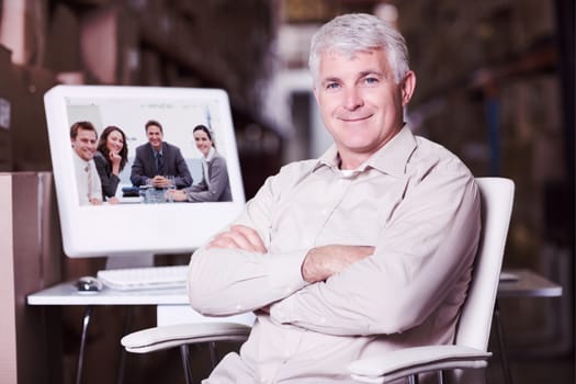 Warehouse manager using computer against portrait of a positive team sitting at a table