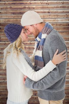Attractive couple in winter fashion hugging against wooden planks