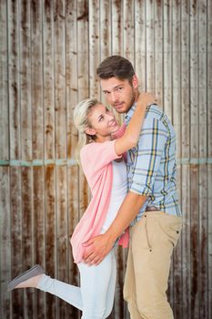 Handsome man hugging his girlfriend against wooden planks