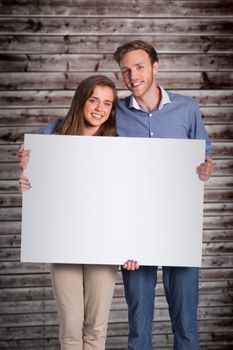 Full length portrait of couple with blank board against wooden planks