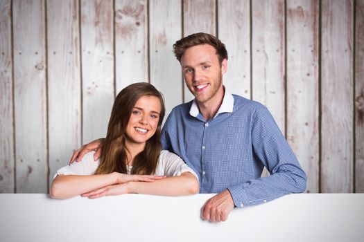 Happy young couple with blank board against wooden planks