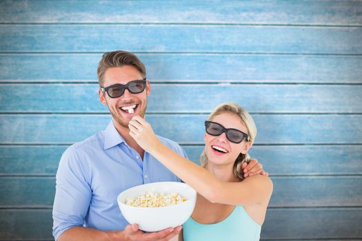 Happy young couple wearing 3d glasses eating popcorn against wooden planks