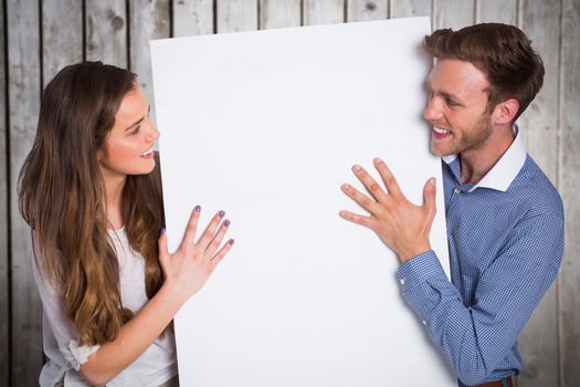 Happy young couple with blank board against wooden planks