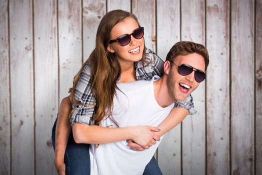 Smiling young man carrying woman against wooden planks