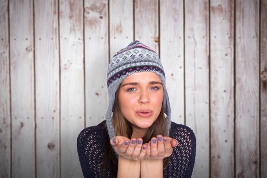 Beautiful woman blowing kiss against wooden planks