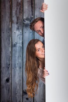 Portrait of young couple with blank board against grey wooden planks